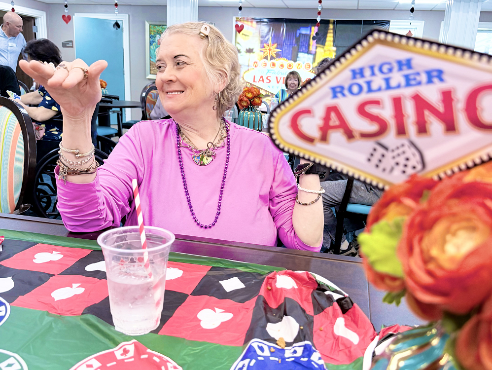A woman enjoys a moment at a table with a casino sign at a skilled nursing and Rehabilitation facility in Shreveport, LA.